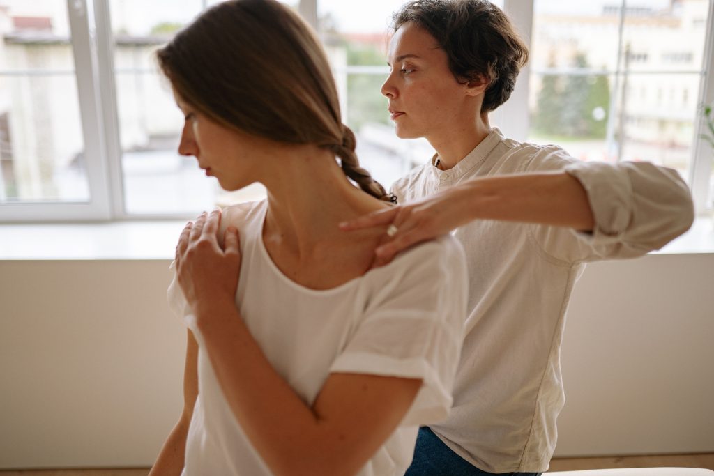 Woman holding her neck and shoulders showing physical signs of trauma stored in the body