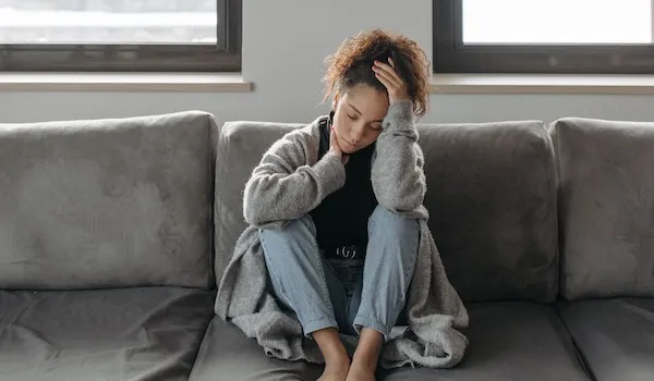 somatic therapy partners woman sitting on sofa with knees to chest woman sitting on sofa with knees to chest